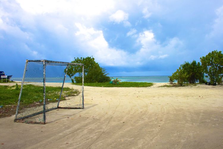 Goal post at sandy beach against sky