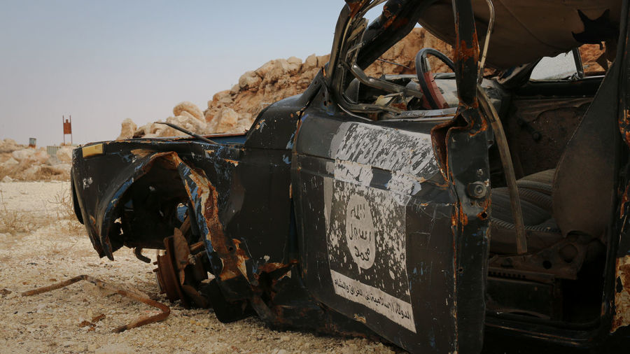 A destroyed isis car. isis flag. war on terror