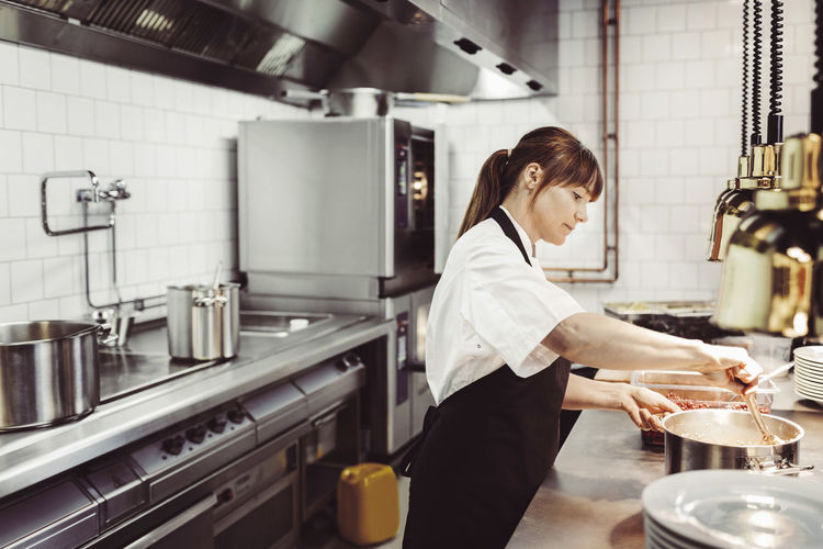 Kvinnlig kock förbereder mat i restaurangkök
