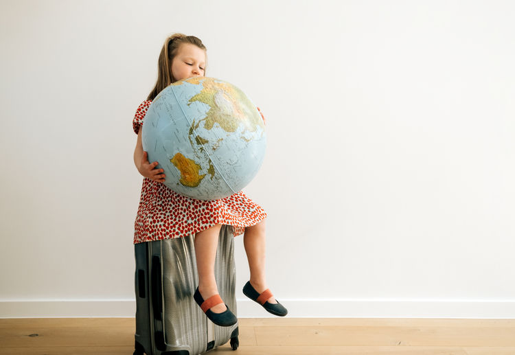 World tourism day concept. girl sitting on a trolley holding a planet and dreaming to travel
