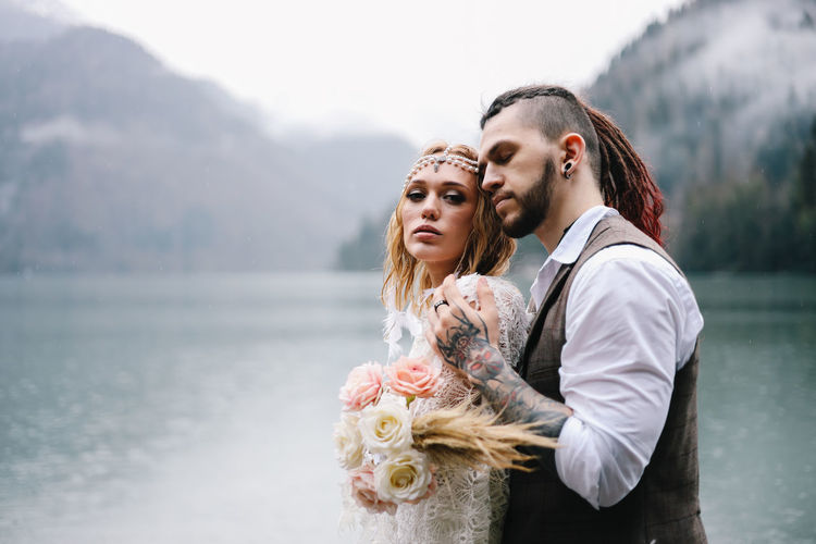 A happy couple in love and married embrace in nature by the lake and the misty mountains