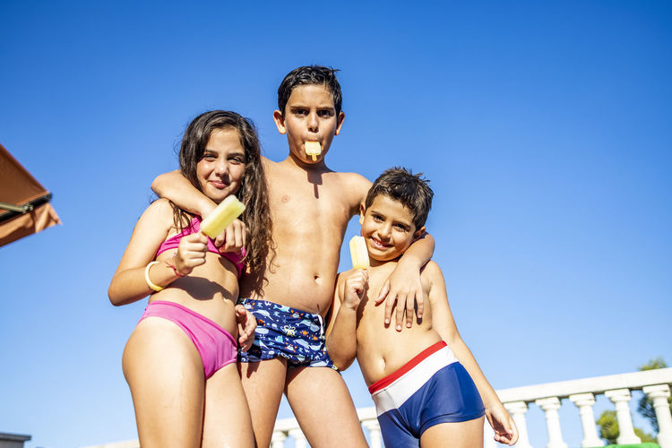 Three funny kids eating an ice lolly