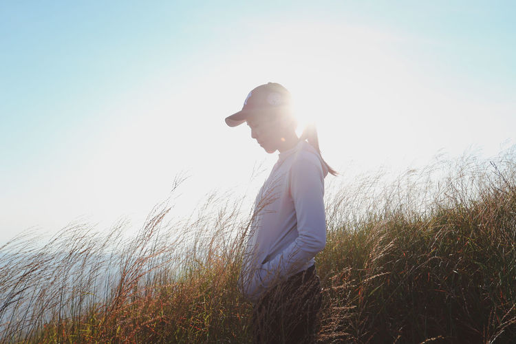 Side view of woman standing amidst plants against sky