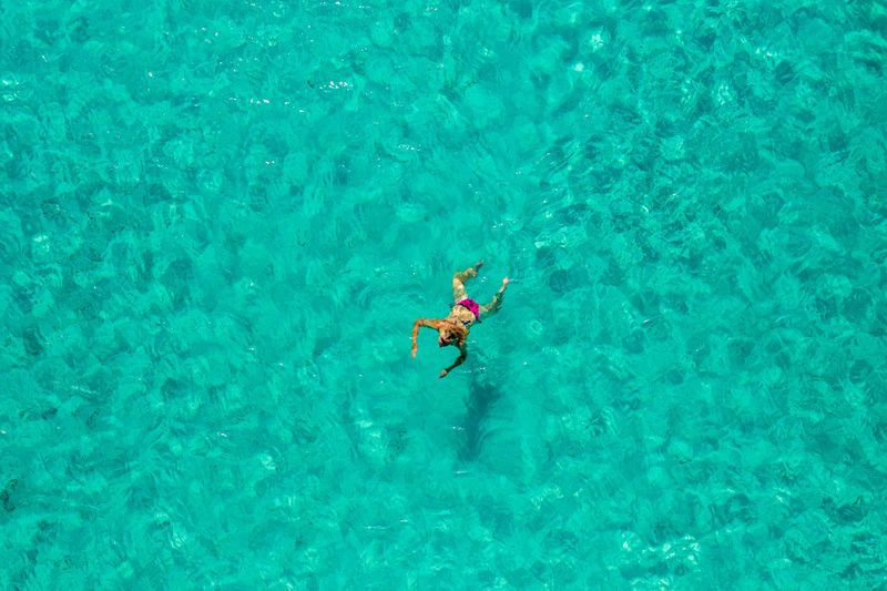 Aerial view of a girl floating in the turquoise sea of the sakarun beach, adriatic sea, croatia