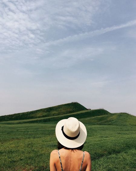 Woman wearing hat on field against sky