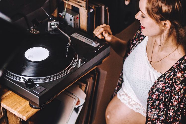 High angle view of pregnant woman playing music on turntable at home