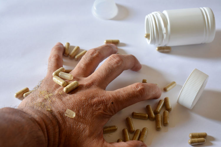 Close-up of hand with capsules on table