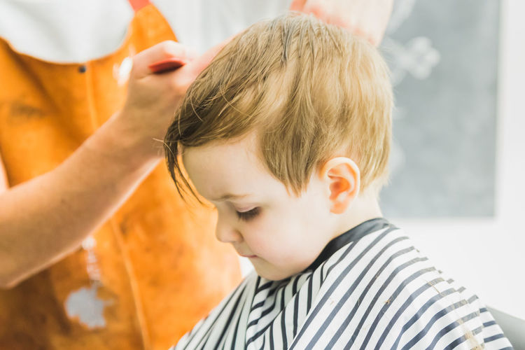 Midsection of barber cutting hair of boy