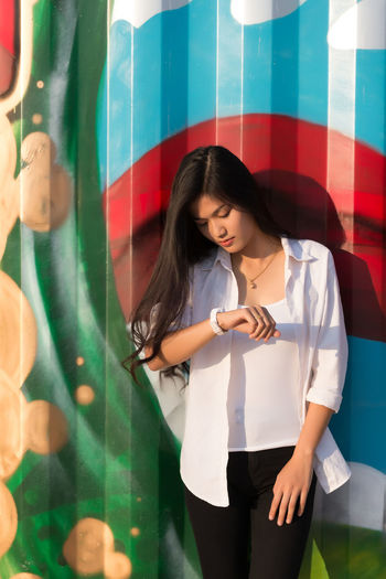 Young woman standing against graffiti