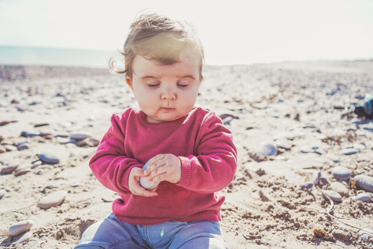 Cute girl sitting on sand at beach