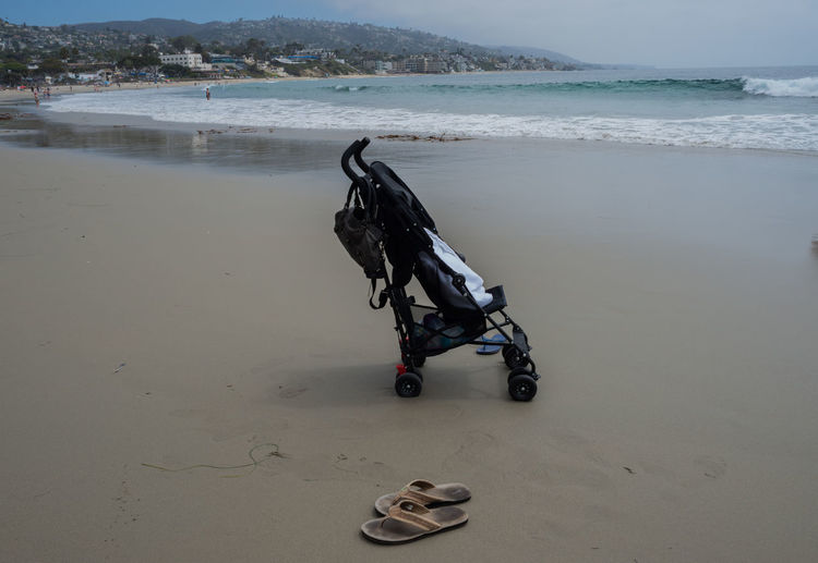 Empty stroller and flip flops at the beach