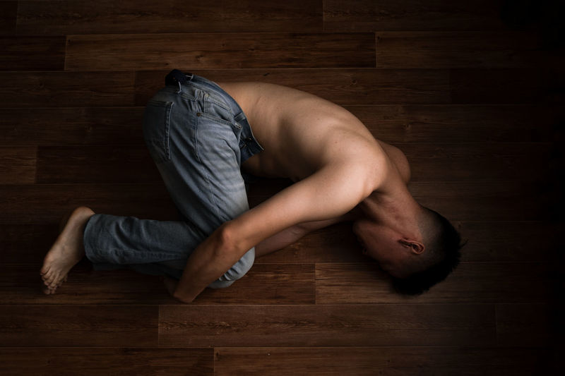 High angle view of man lying on hardwood floor