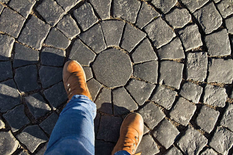 Low section of man standing on cobblestone street