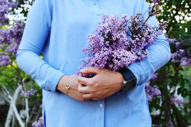 Low angle view of person holding purple flowering plant