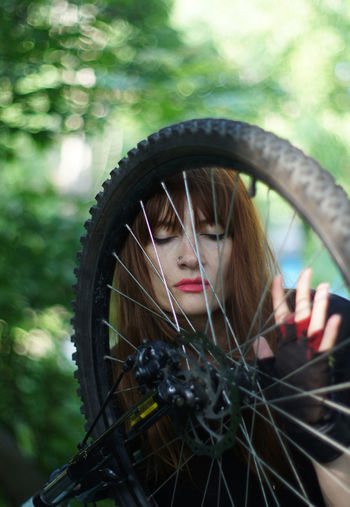 Portrait of woman behind bicycle wheel