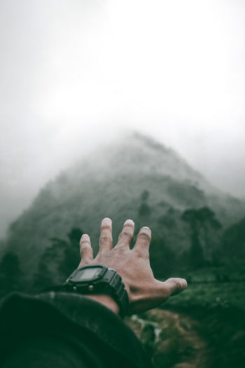 Cropped hand of man against mountain