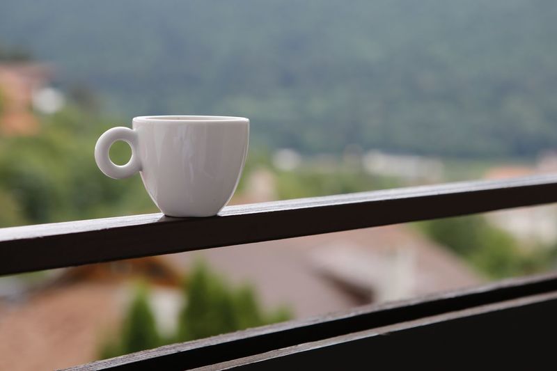 Close-up of coffee cup on railing