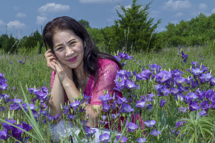 Portrait of smiling woman on purple flowering plants on field