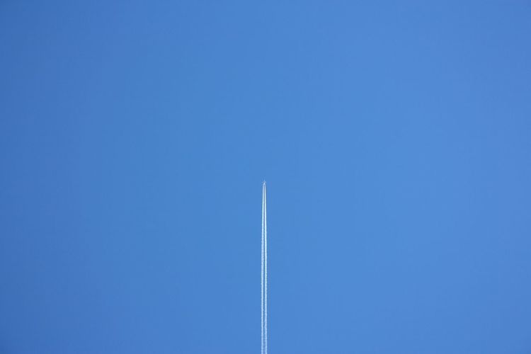 White trail of a plane far away in the blue sky landscape