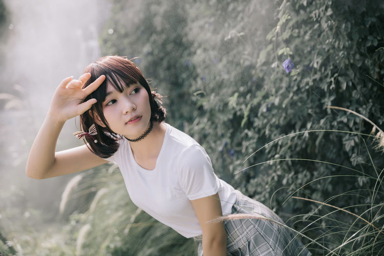 Beautiful young woman looking away while standing in forest