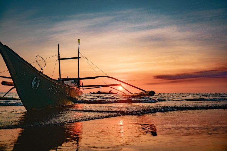 Fishing boat on sea during sunset