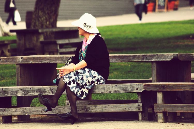 Full length of woman sitting on bench at park