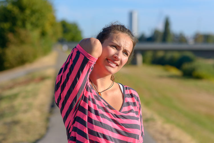 Young woman with back ache standing on road