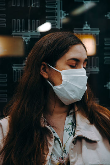 Portrait of young woman with eyes closed wearing a face mask inside an underground train