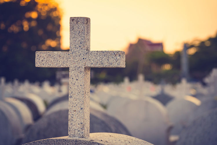 Close-up of cross in cemetery against sky