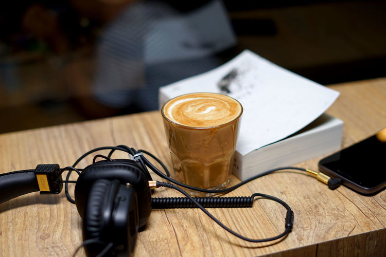 Desk table in coffee shop with headphones ,book and coffee