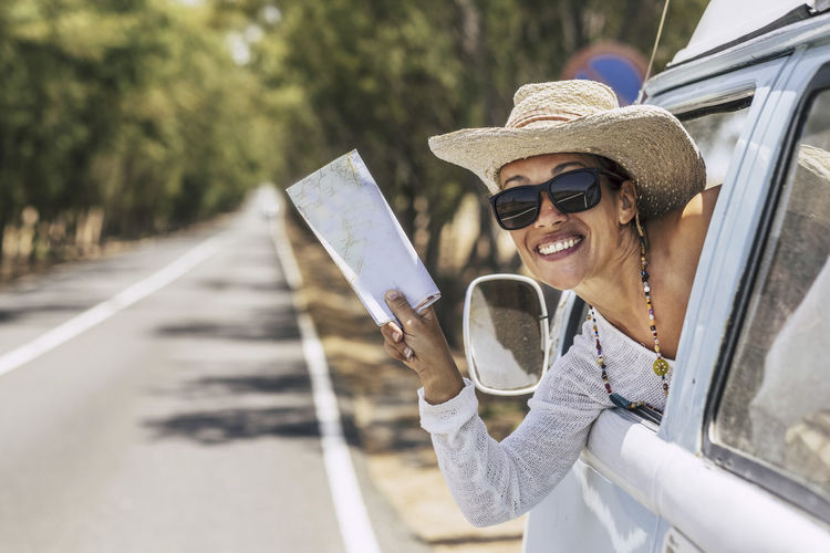 Portrait of smiling woman holding map in car