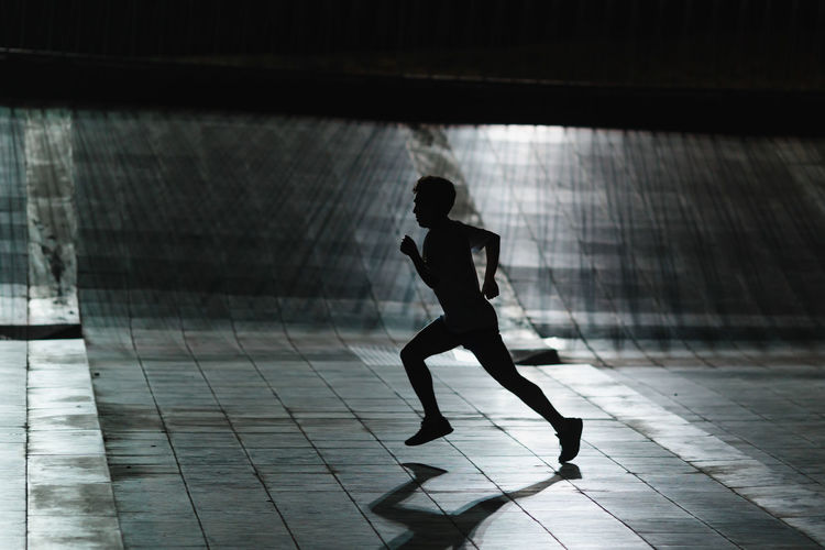 Full length of silhouette man running in tunnel