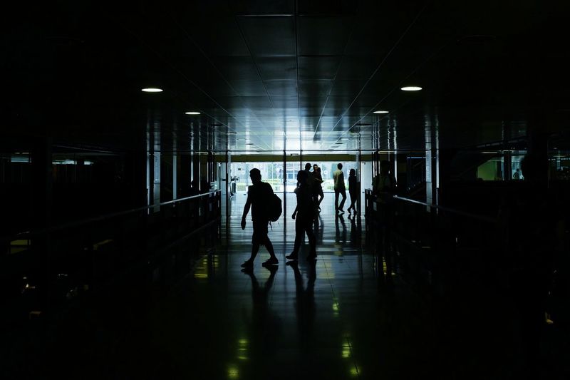 Silhouette people walking in illuminated city at night