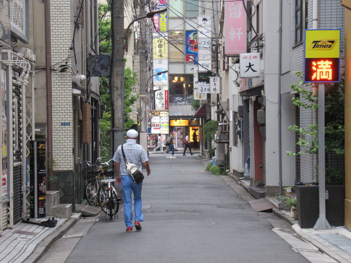 Rear view of men walking on street amidst buildings