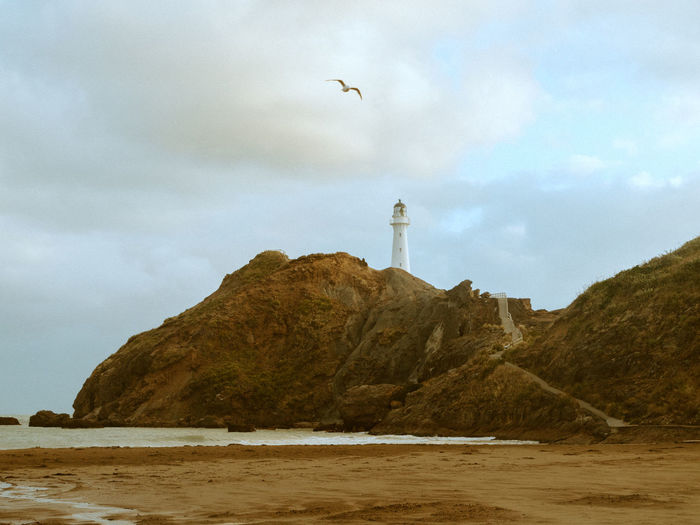 View of lighthouse by sea against sky
