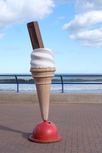 Close-up of ice cream on beach against sky