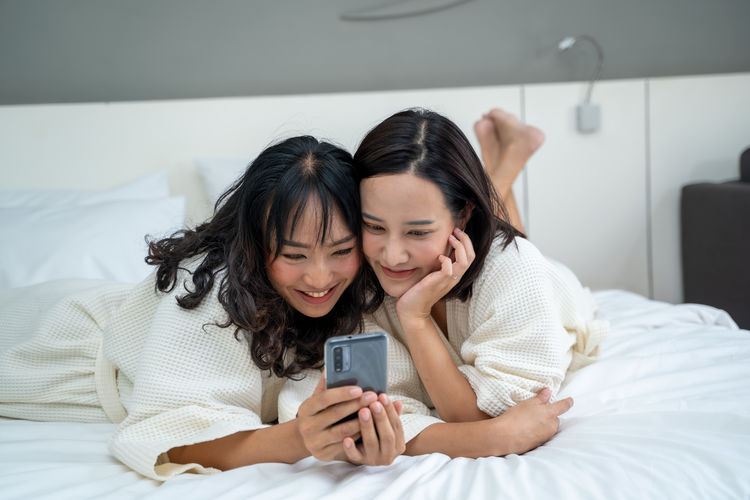 Woman using mobile phone while sitting on bed