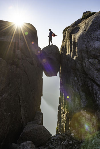 Man standing on rock amidst cliff against sky