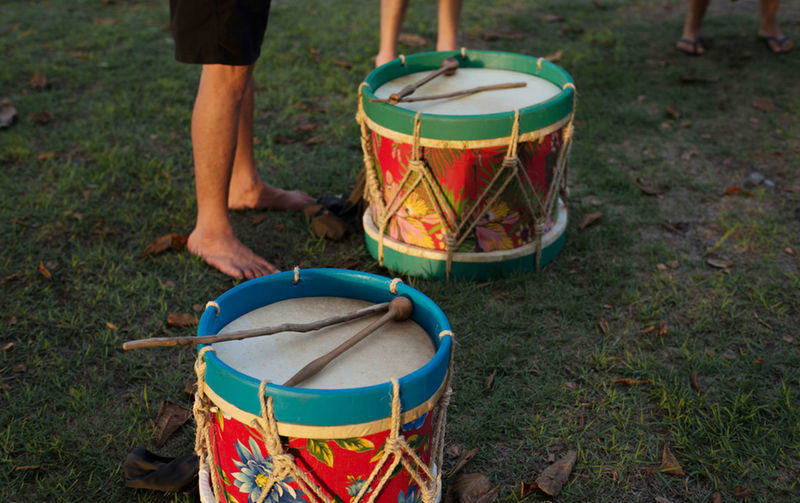 Low section of man beside handmade drums on the grass