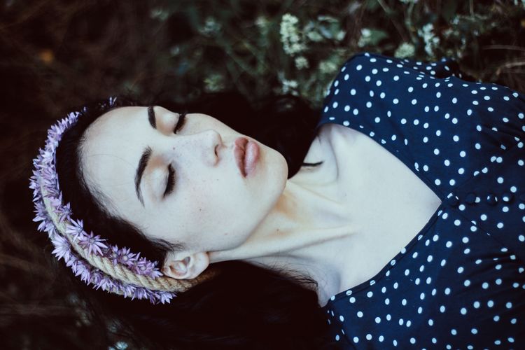Close-up of young woman with eyes closed wearing flowers