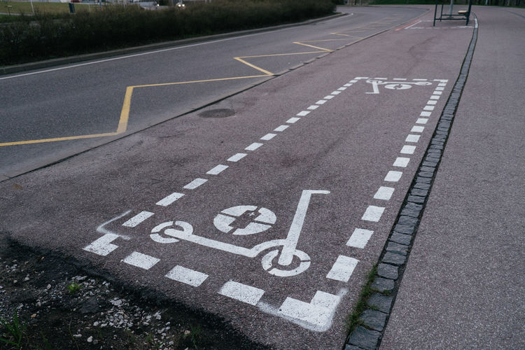 Dedicated electric scooter parking spot sign spray painted on city sidewalk.