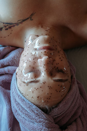 Close-up portrait of young woman applying peel off mask for facial cleansing and spa treatment.