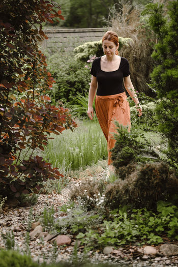 Happy ginger hair woman walking barefoot in the park or garden. freedom and healthy way of life
