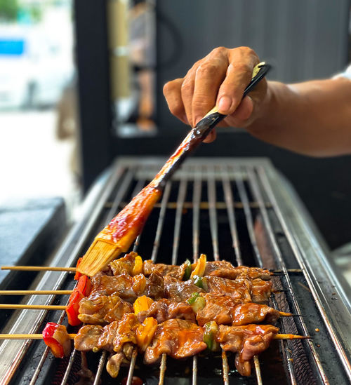 Cropped image of person preparing food on barbecue grill