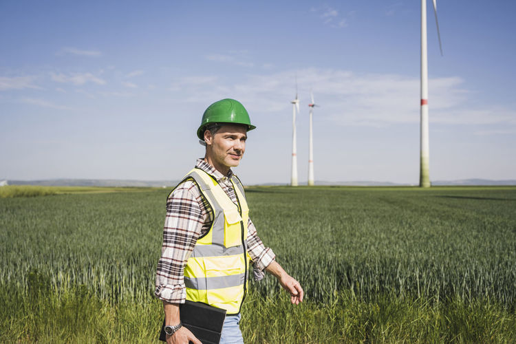 Mature engineer wearing hardhat walking on field