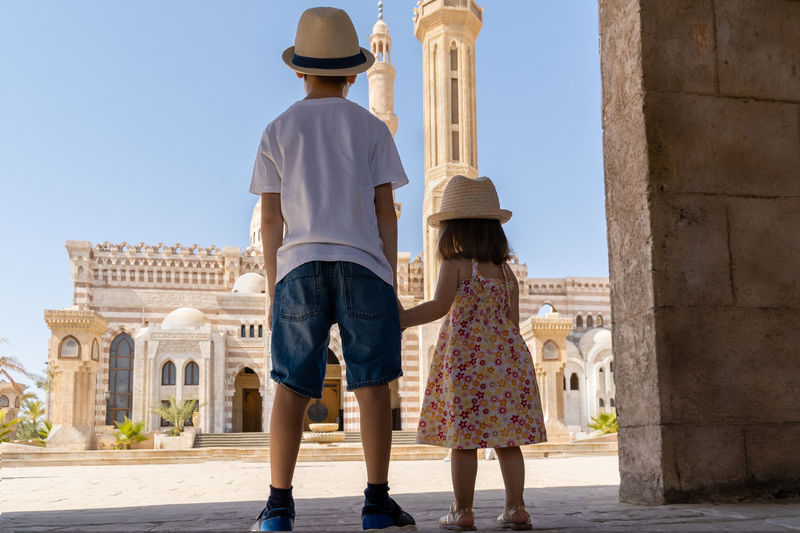 A boy and a girl standing in front of el mustafa mosque and looking at it