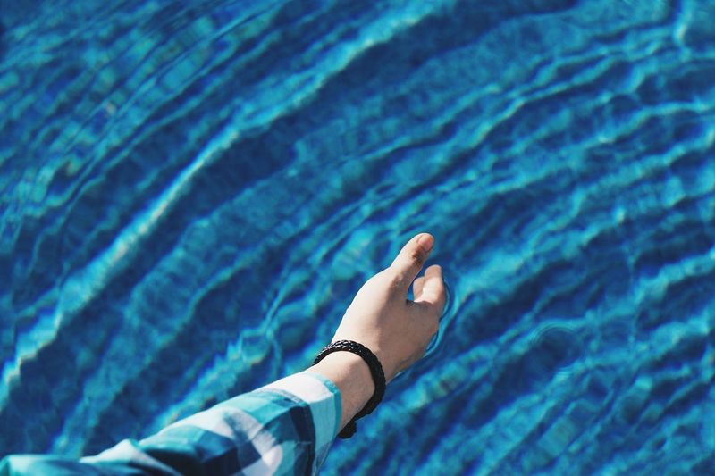 Cropped hand of man by swimming pool