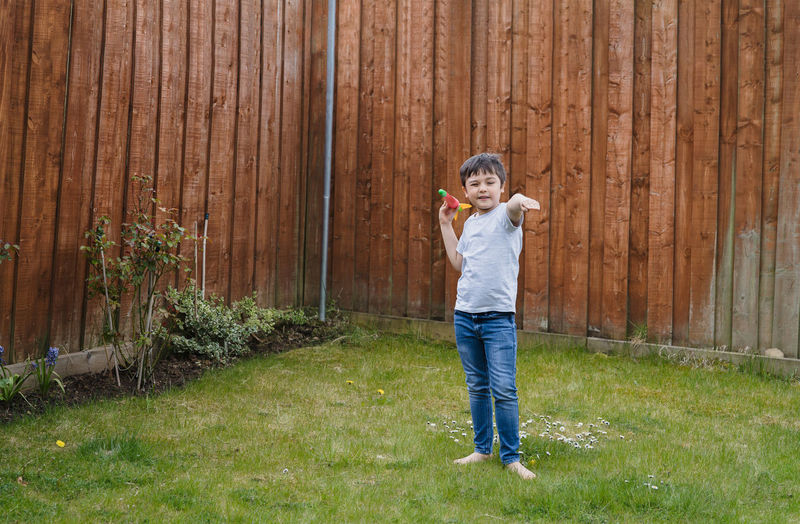 Full length portrait of boy standing by fence