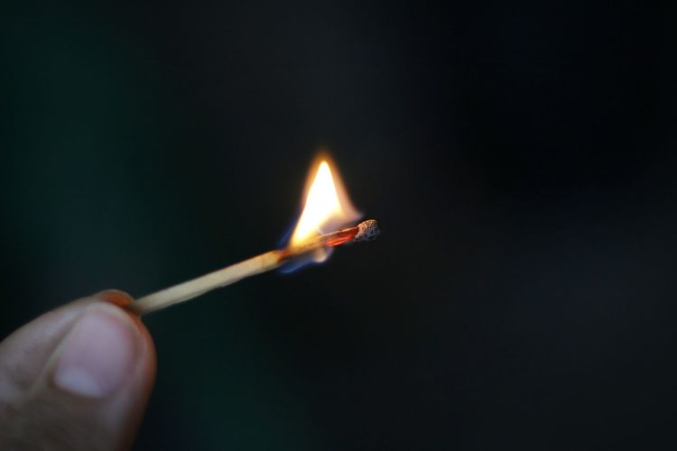 Close-up of hand holding burning match