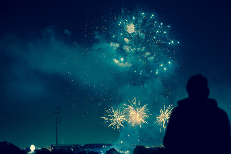 Silhouette of fireworks against sky at night